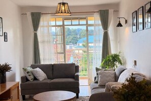 Una sala de estar con un sofá, una mesa de centro y vistas amplias a través de grandes ventanales.