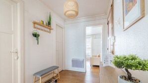 Ein Flur mit einer Bank, einem Blumentopf, einem Regal mit Dekoration und einer Tür.