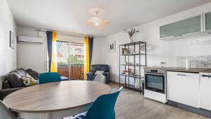 Una cocina moderna con armarios blancos, horno empotrado y comedor con mesa y sillas redondas.