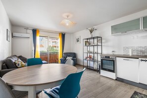A modern kitchen with white cabinets, a built-in oven, and a dining area with a round table and chairs. - L'Instant Sétois - Avec Terrasse et Parking (Sète)