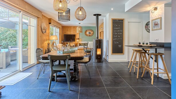 Una cocina moderna con comedor, ventanas amplias y un patio exterior visible.