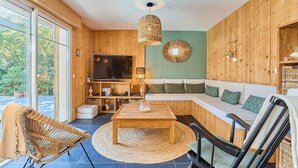 Una sala de estar acogedora con suelo de madera, un sofá, una mesa de centro y un televisor.