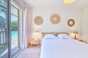 A bedroom with a bed, two bedside tables, a window with a view, and three wall-mounted circular mirrors. - Villa Rose - Au cœur du Ferret avec Piscine Privée (Lège-Cap-Ferret)