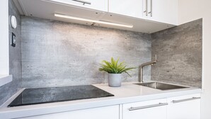 Een moderne keuken met een achterwand van beton, een roestvrijstalen spoelbak en een potplant.