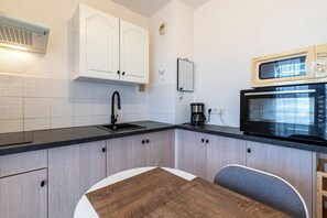 Eine kleine Küche mit Spüle, Mikrowelle und Kaffeemaschine.