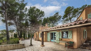 A stone-paved courtyard with a rustic building featuring green shutters and a tiled roof. - Hameau des Laurons - Climatisée, piscine privée (Tourtour)