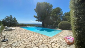 A swimming pool with stone tiles, lounge chairs, and a view of the landscape. - Hameau des Laurons - Climatisée, piscine privée (Tourtour)