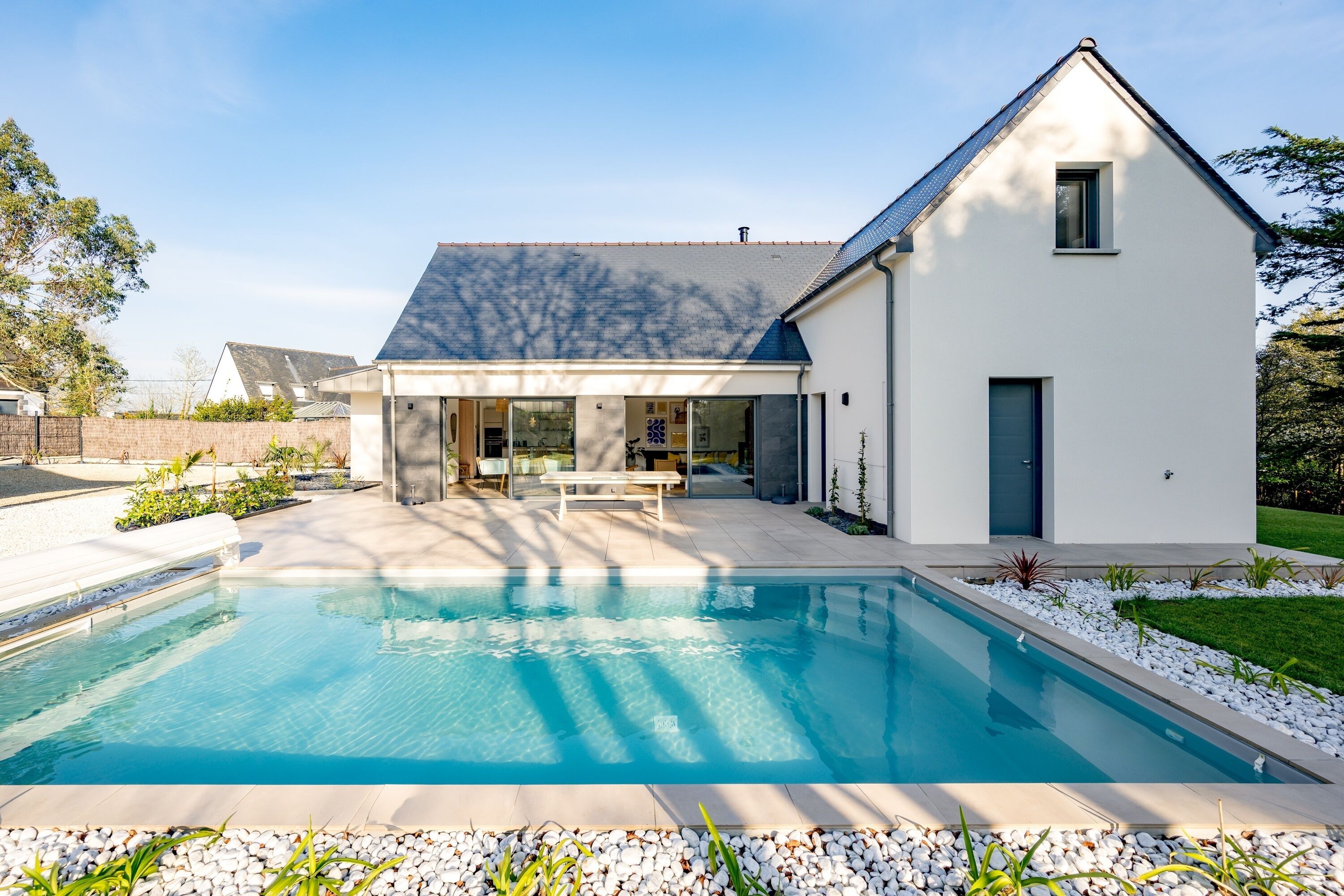 Une maison moderne dotée d’une piscine, d’un patio et d’une pelouse bien entretenue.
