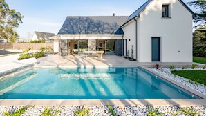 A modern house with a swimming pool, a patio, and a well-maintained lawn.