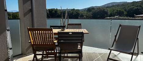 Una terraza con mesa y sillas, vistas a un lago y una silla para tomar el sol.