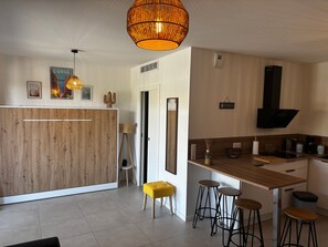 Una cocina moderna con una isla de madera, taburetes de bar y una lámpara colgante.