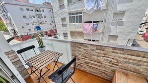 A balcony with a wooden table and chairs, a potted plant, and a view of neighboring buildings. - Poppy of SteraM Flats Torremolinos (Torremolinos)