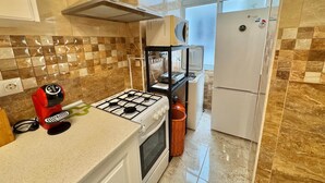 A kitchen with a gas stove, oven, and a refrigerator. - Poppy of SteraM Flats Torremolinos (Torremolinos)