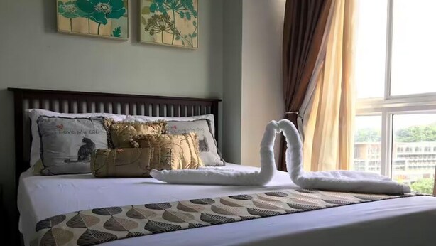 Une chambre d’hôtel avec un lit, des coussins décoratifs, une couvre-lit à motifs et des œuvres d’art accrochées au mur.