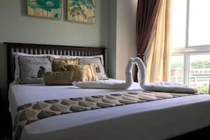 Une chambre d’hôtel avec un lit, des coussins décoratifs, une couvre-lit à motifs et des œuvres d’art accrochées au mur.
