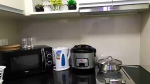 Une cuisine équipée d’un four à micro-ondes, d’un cuiseur à riz et d’une cuisinière.