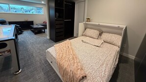A bedroom with a bed, a desk, a wardrobe, and a view of the outside. - Near Vancouver: Backyard Cinema + Game (Delta)
