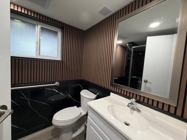 A bathroom with a toilet, sink, and bathtub. - Near Vancouver: Backyard Cinema + Game (Delta)