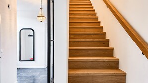 A wooden staircase with a handrail, a chandelier, and a mirror on the wall. - Cozy home in Detern with WiFi (Detern)
