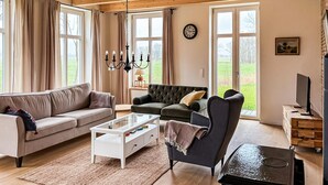 A living room with a sofa, armchair, coffee table, and TV stand. - Cozy home in Detern with WiFi (Detern)