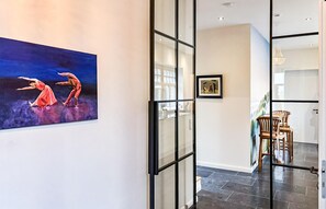 A modern interior with a glass partition, a framed artwork, and a dining area with chairs. - Cozy home in Detern with WiFi (Detern)