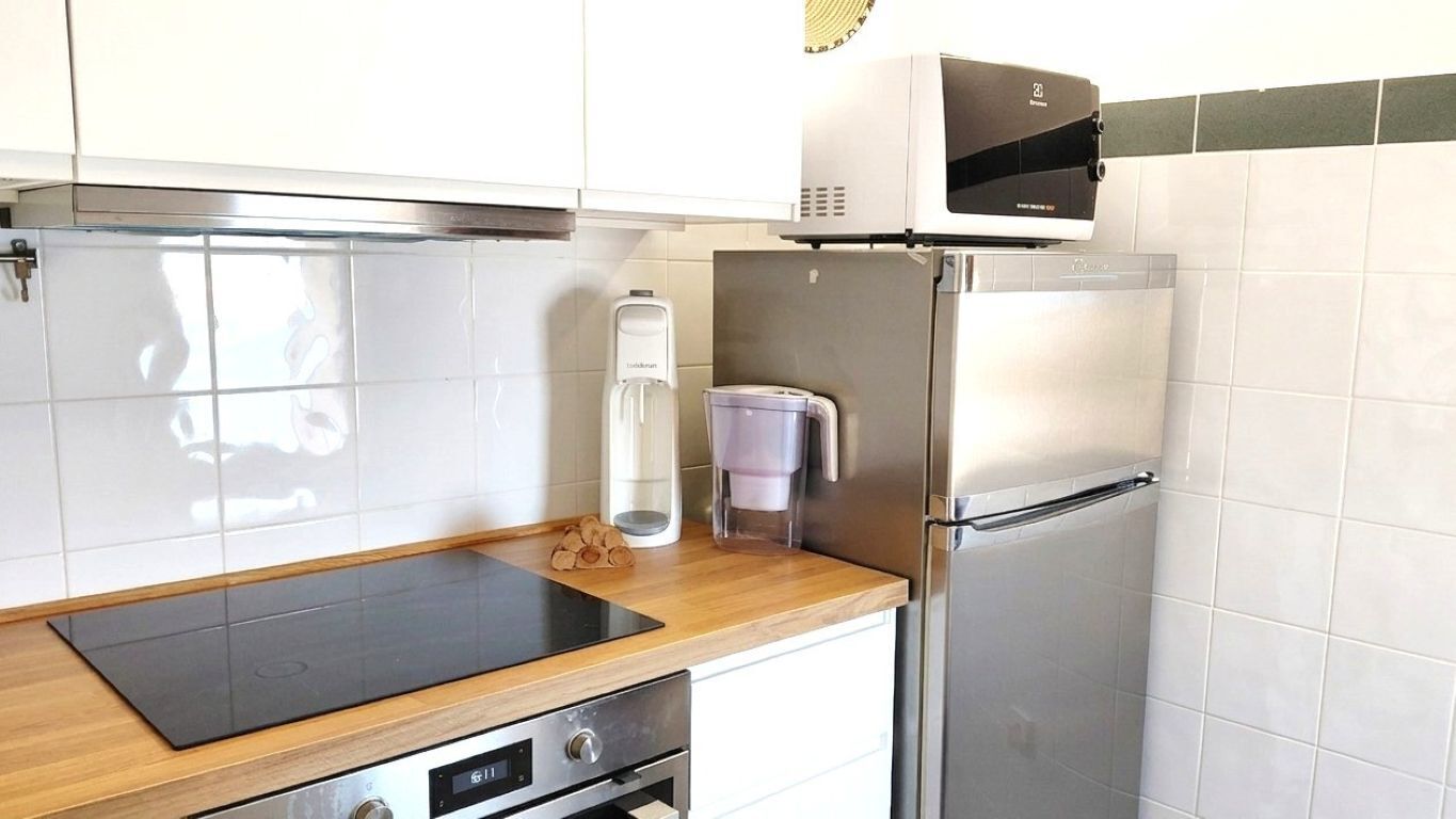 A kitchen with a stainless steel refrigerator, a built-in microwave, a coffee maker, and a wooden countertop.