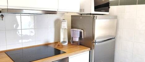 A kitchen with a stainless steel refrigerator, a built-in microwave, a coffee maker, and a wooden countertop.