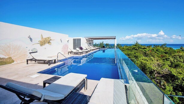 A swimming pool with lounge chairs, a pergola, and a view of the ocean. - Big Terrace Luxury 2-bedroom condo in charming Playa del Carmen with AC (Playa del Carmen)