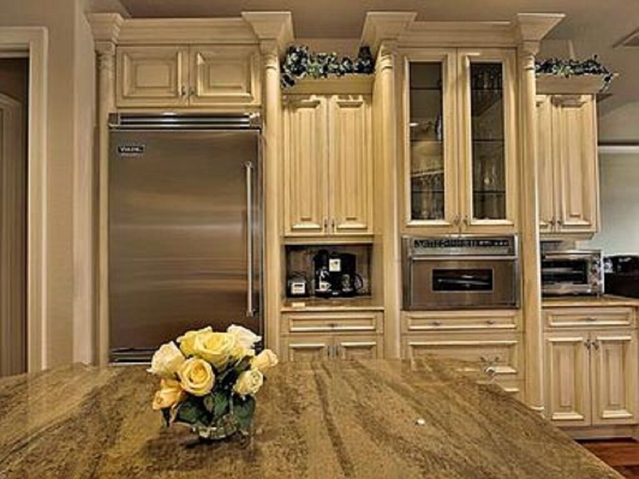 A kitchen with a marble countertop, stainless steel appliances, and light-colored cabinetry.