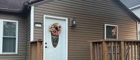 A residential house with a front door, a wooden porch, and a mailbox.
