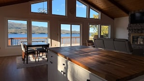 A kitchen with a wooden countertop, white cabinets, and a view of a lake through large windows. - Waterfront Fishing Lodge | 2BR | Dockside Charters (Ketchikan)
