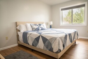 Um quarto com uma cama, uma janela e uma mesa de cabeceira.
