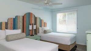 A bedroom with two beds, a ceiling fan, a window with blinds, and a decorative headboard. - 2-bedroom hotel suites in terrific Anaheim with fitness room and AC (Anaheim)