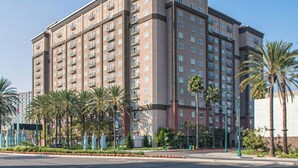 A multi-story hotel with balconies, palm trees, and a clear sky. - 2-bedroom hotel suites in terrific Anaheim with fitness room and AC (Anaheim)
