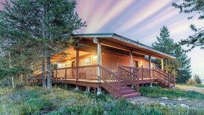 A wooden cabin with a porch, stairs, and a view of the surrounding forest. - Yellowstone Park in 30 mins with Sauna & Hot Tub (Island Park)