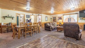 A wooden-paneled room with a dining table, chairs, a sofa, and a television. - Yellowstone Park in 30 mins with Sauna & Hot Tub (Island Park)