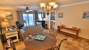 Una sala de estar con una mesa redonda, sillas, un sofá, un televisor y un balcón con vistas.