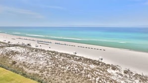 Una playa con orilla de arena, cielo despejado y una hilera de sombrillas.