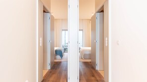 Un pasillo que conduce a un dormitorio con una cama, una silla y un ventanal.