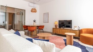 Un salon moderne comprenant un canapé, des fauteuils, un téléviseur et un coin repas.