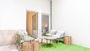 Un petit espace extérieur aménagé, délimité et doté d’une pelouse artificielle, de paniers en osier et d’un coin salon avec des chaises et une table.
