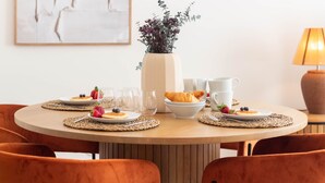 Une table ronde où sont disposés des assiettes remplies de nourriture, des verres et un vase de fleurs.