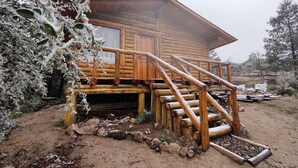 A wooden cabin with a wooden staircase leading to a porch.