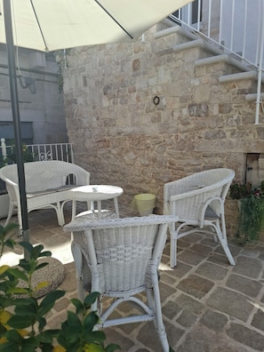 A stone wall with a decorative metal piece, wicker furniture, and a staircase. - Tower Slope b&b (Corato)