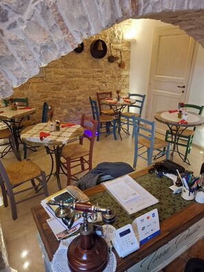 Een gezellig restaurant met stenen muren, houten meubels en verschillende eettafels en stoelen.