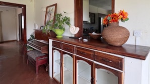 Une pièce avec un comptoir en bois, un miroir, une plante en pot, un vase de fleurs et un banc.