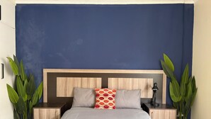 Une chambre à coucher avec un lit, deux tables de chevet, une tête de lit en bois et deux plantes en pot.