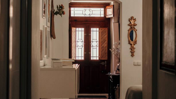 An arched hallway leading to a room labeled 'SALIDA' with framed pictures, a mirror, and a small table with a vase. - Casa Boutique ALEGRÍA, aromas and art. (Caudete de las Fuentes)