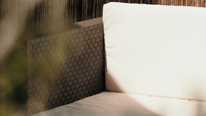 A white sofa with a textured backrest in a room with a bamboo wall. - Casa Boutique ALEGRÍA, aromas and art. (Caudete de las Fuentes)
