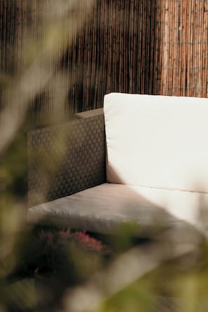 Un sofá blanco con respaldo texturizado en una habitación con pared de bambú.
